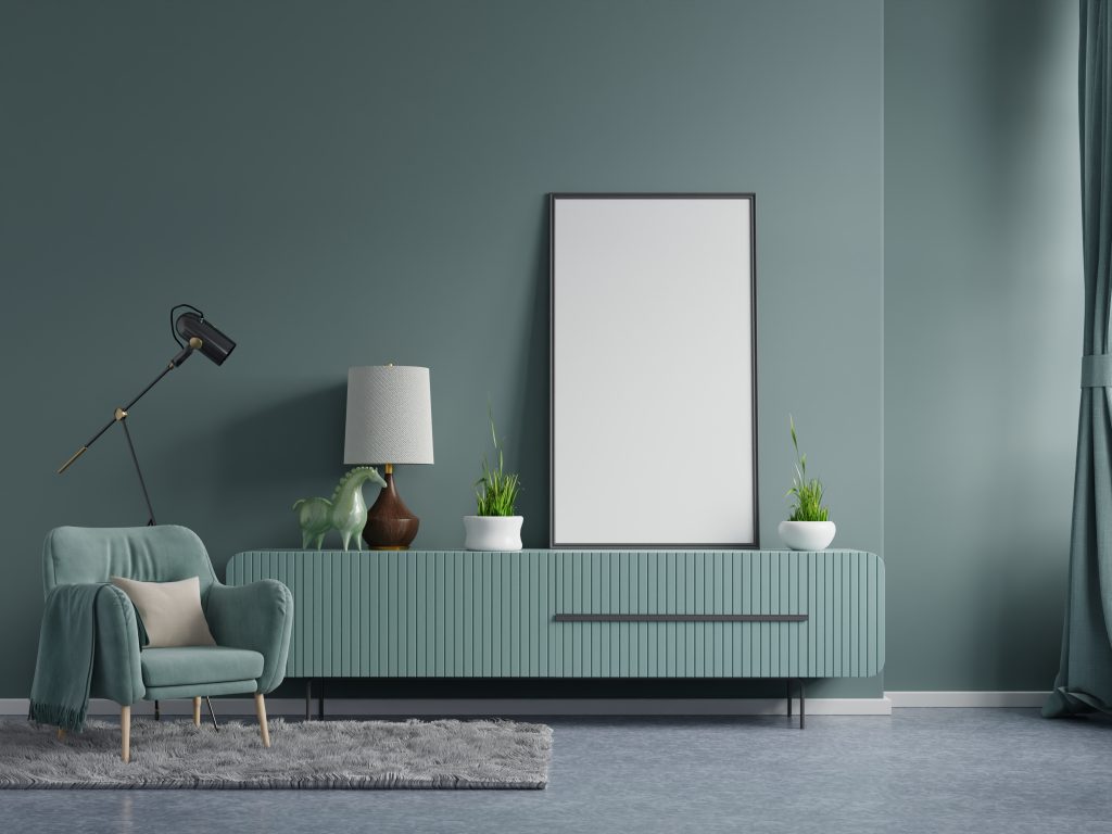 Poster mockup with vertical frames on empty dark green wall in living room interior with dark green velvet armchair.